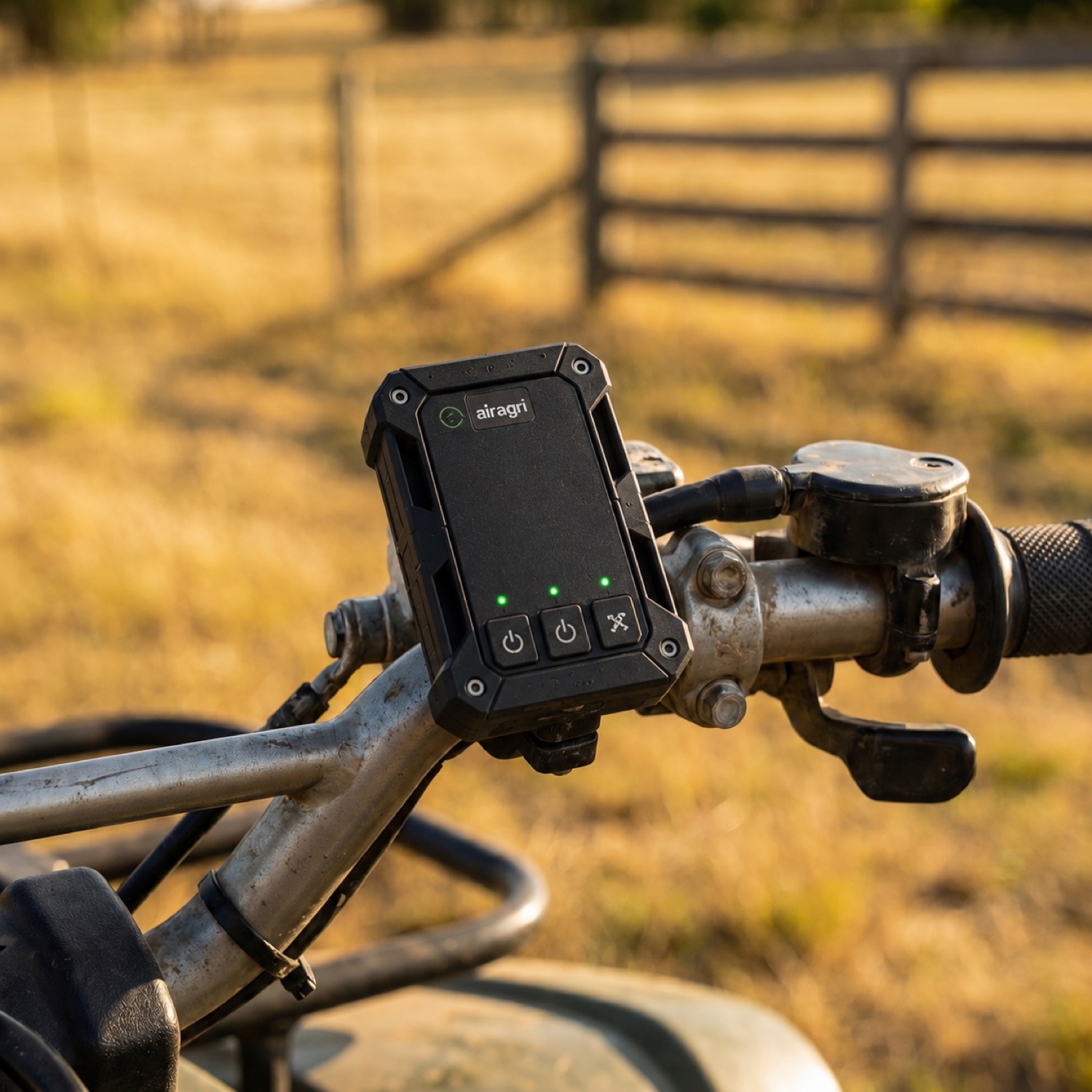 An AirAgri satellite safety tracker mounted on a quad-bike handlebar, status lights lit, in a golden paddock.